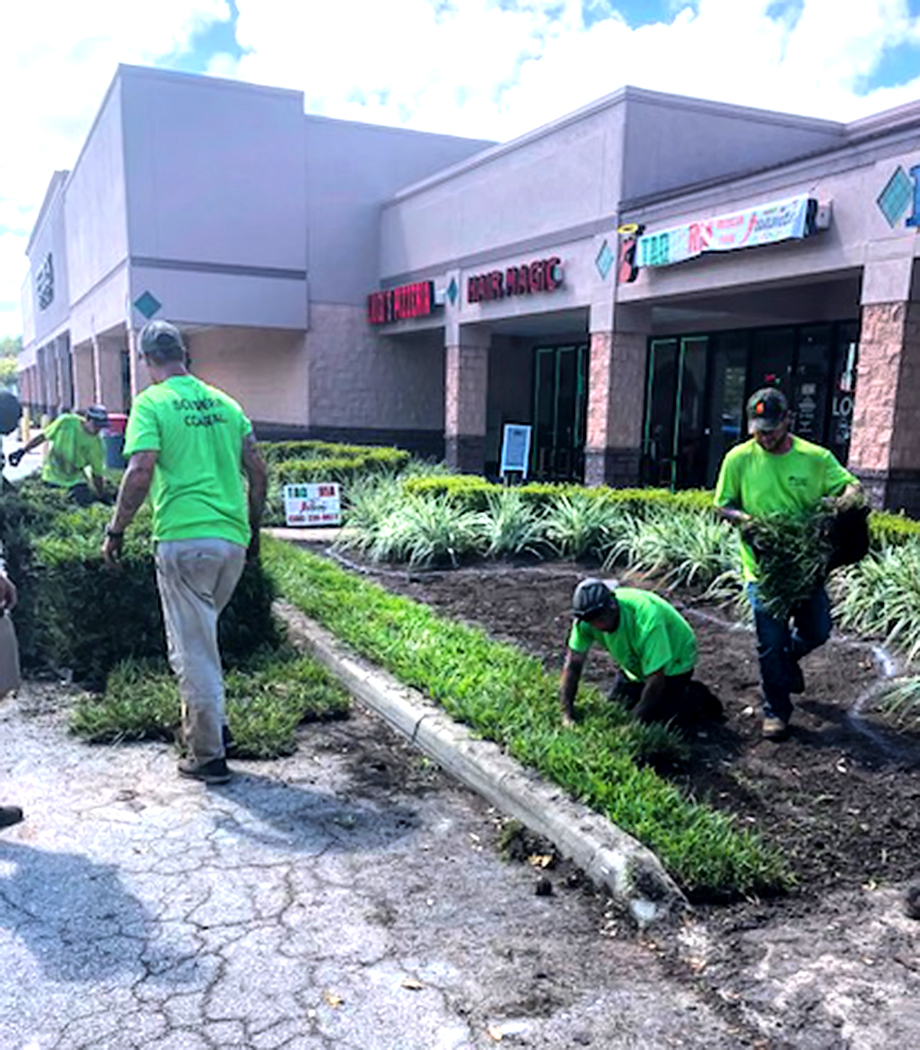 Southern Coastal Property Maintenance workers installing a mulch bed in front of a commercial property.